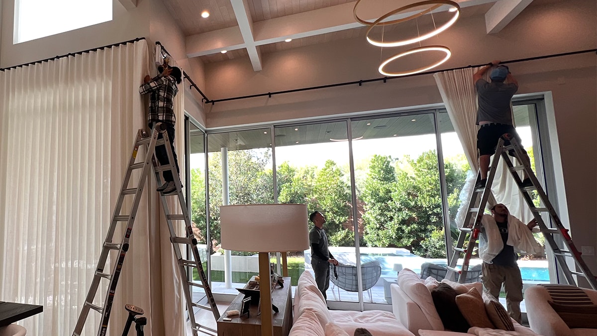 Caribbean Window Designs installers fitting drapery in a Naples great room